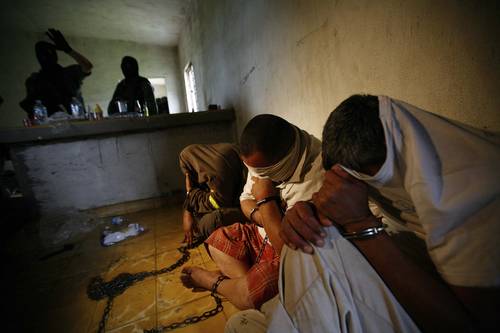 Soldier stands guard next to people kidnapped by drug hitmen at a ranch near the municipality of Sabinas Hidalgo